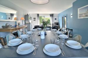 a dining room with a table with plates and wine glasses at Spacieuse maison avec piscine proche plage à Canca in Cancale