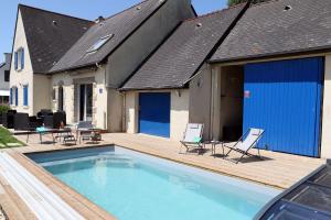 a swimming pool with chairs and a house at Spacieuse maison avec piscine proche plage à Canca in Cancale