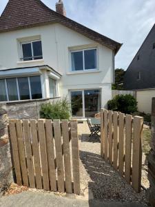 a house with a wooden fence in front of it at Villa Denise Petit Gîte in Barneville-Carteret