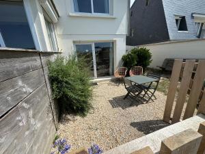 a patio with a table and chairs in front of a house at Villa Denise Petit Gîte in Barneville-Carteret