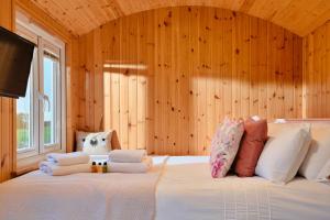 a bedroom with a large white bed with wooden walls at Finest Retreats - Demelza Shepherds Hut in Grade