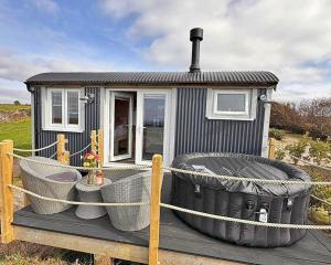 a small house with a tub on a deck at Finest Retreats - Demelza Shepherds Hut in Grade