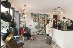 a woman sitting in a chair with a suitcase in a salon at Best Western Plus Opéra Batignolles in Paris