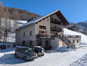 two cars parked in front of a house in the snow at Ailleurs La Chalp à Saint-Véran in Saint-Véran
