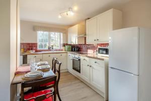 a kitchen with a table and a white refrigerator at 2 Bed in Bressingham oc-f33646 in Bressingham +12 photos