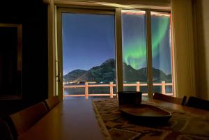a dining room table with a view of the northern lights at Modern seafront cabin with sauna 8 mins to Leknes in Storeidet