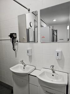 a white bathroom with two sinks and a mirror at TomTom Hostel in Krakow