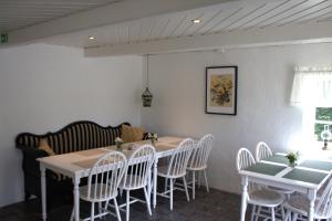 a dining room with white tables and white chairs at Landet Bed and Breakfast in Tomelilla