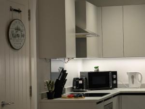a kitchen with white cabinets and a microwave at Two Bedroom Flat with Ensuite Bathrooms in Hemel Hempstead