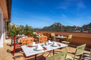 a patio with tables and chairs with mountains in the background at Antica Dimora La Corona in San Pantaleo
