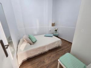 a small white room with a bed and a chair at La Perlita in Las Eras