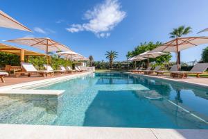 a swimming pool with chairs and umbrellas at Villa Carlotta Resort in San Leone