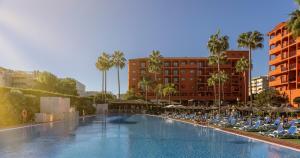 a large swimming pool with chairs and umbrellas at ILUNION Miramar in Fuengirola