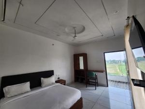 a bedroom with a bed and a window and a chair at Raj Embassy in Rudrapur