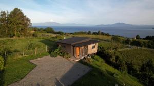 a small house on a hill with mountains in the background at Parcela Nueve in Frutillar