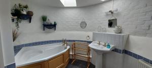 a bathroom with a tub and a sink at Whitewells Farm Cottages - 7 exceptionally well appointed pet friendly barn conversions set in 10 acres of gardens, fields and woodland suitable from 2 to 24 people with breathtaking views towards the Malvern Hills, Herefordshire and Worcestershire in Mathon +98 photos