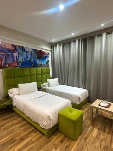 a bedroom with two beds and a green wall at Hotel Annasr in Chefchaouen