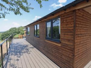 a wooden cabin with windows on a deck at The Cabin - Private Car Park with CCTV - Fast WiFi - Peaceful Retreat with Views for Business or Couples in Oldbury