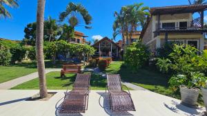 two benches sitting on a sidewalk in front of a house at Pousada Vila Bacana in São Miguel do Gostoso