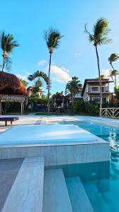 a swimming pool with palm trees in the background at Pousada Vila Bacana in São Miguel do Gostoso