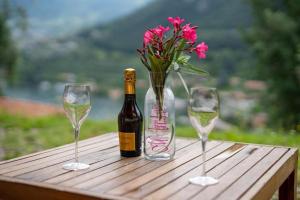 a bottle of wine and two glasses and a vase with flowers at NIC Lake House in Sulzano