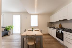 a kitchen with a table and a kitchen with white cabinets at Dama Apartments in San Vito di Leguzzano