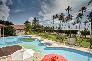 a resort swimming pool with umbrellas and palm trees at Turyaa Kalutara in Kalutara