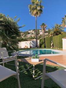 a swimming pool with two chairs and a table and a tablektop at Casa Laura by Sun & Sea Homes in Moraira