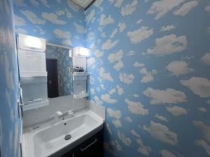 a bathroom with a sink with clouds on the wall at Hillshouse2はなれ in Tokoname +25 photos