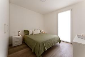 a white bedroom with a bed and a window at Dama Apartments in San Vito di Leguzzano