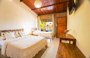a bedroom with two beds and a large window at Pousada Bicho Preguiça in Pipa