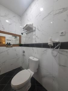 a white bathroom with a toilet and a phone on the wall at Comfy Room Yogyakarta BY Hamsa Putih in Yogyakarta +11 photos