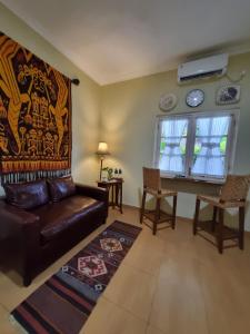a living room with a leather couch and a table at Comfy Room Yogyakarta BY Hamsa Putih in Yogyakarta