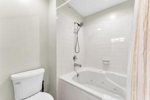 a white bathroom with a toilet and a bath tub at Branson 2BR Retreat | Jacuzzi + Gym + Pools in Hollister +9 photos