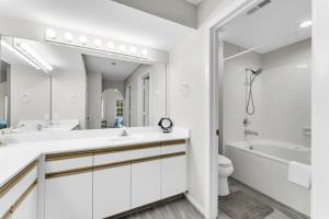 a white bathroom with a tub and a sink and a toilet at Branson 2BR Retreat | Jacuzzi + Gym + Pools in Hollister