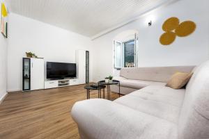 a white living room with a couch and a tv at Apartment Alen in Makarska