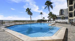 a swimming pool with palm trees and a building at Mariner's Boathouse and Beach Resort by CoolVacay in Fort Myers Beach