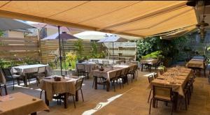 a restaurant with tables and umbrellas on a patio at Logis Hôtel - Auberge les Clarines in Le Châtelard