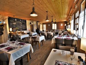 a restaurant with white tables and chairs and a chalkboard at Logis Hôtel - Auberge les Clarines in Le Châtelard