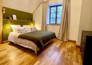a bedroom with a bed with a green headboard and a window at La Villa de Paul - Les Chambres in Yenne +20 photos