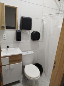 a white bathroom with a toilet and a sink at Republica Fusinato in Itajaí