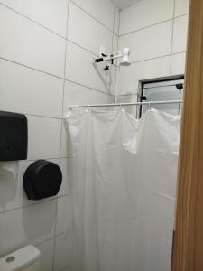 a white shower curtain hanging in a bathroom at Republica Fusinato in Itajaí +3 photos