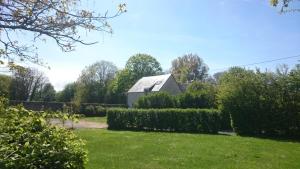 a white barn in a garden with bushes and trees at Gîte Le Val de Marigny 2 personnes in Longues-sur-Mer