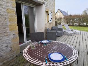 a table with plates and glasses on a wooden deck at Gîte Le Val de Marigny 2 personnes in Longues-sur-Mer