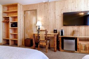 a bedroom with a desk with a television and a bed at Adirondack Spruce Lodge in Wilmington