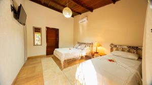 a bedroom with two beds and a flat screen tv at Pousada Bicho Preguiça in Pipa