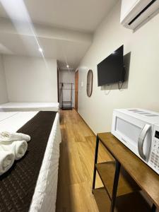 a room with a bed and a microwave on a table at Suítes Viver Arraial do Cabo in Arraial do Cabo