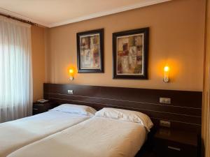 a bedroom with two beds and two pictures on the wall at Hotel Santa Teresa in Ávila