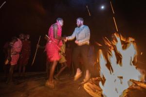 a man and a woman standing in front of a fire at Entalet Mara Camp in Talek