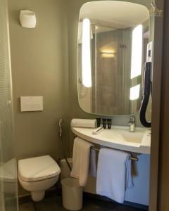 a bathroom with a sink and a toilet and a mirror at Atlantis Alger Aéroport ex Ibis in Alger +32 photos